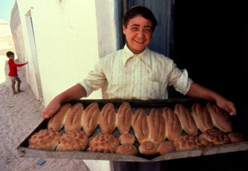 Garçon portant une fournée de pains.