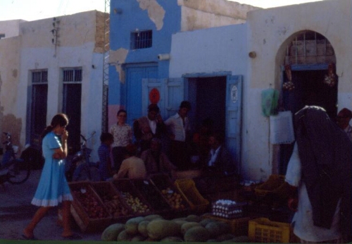 Vue d'ensemble du marché de la Hara Kebira, avec passants, étals et vendeurs dans leurs échoppes bleues