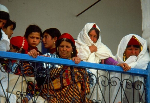 Scène intérieure: femmes en habit traditionnel et jeunes filles au balcon de la synagogue de la Ghriba